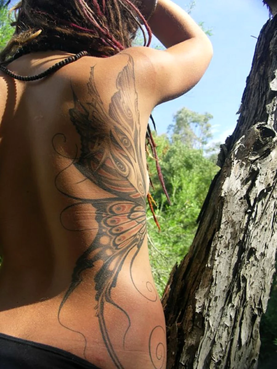 Татуировка на спине и боку. Красивая девушка
